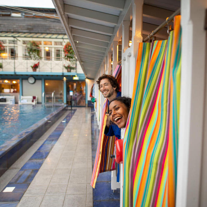 Man and woman peek out of changing rooms before going for a swim