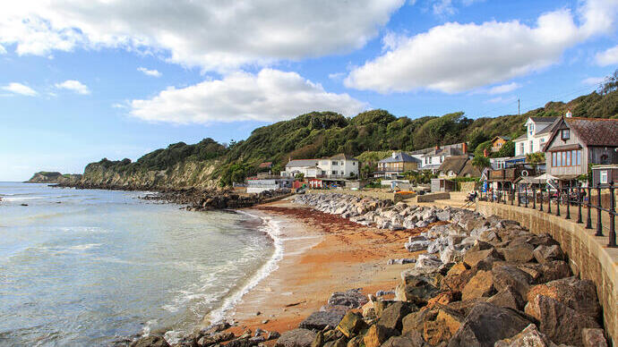 Küste mit Sand und Häusern in einer Bucht