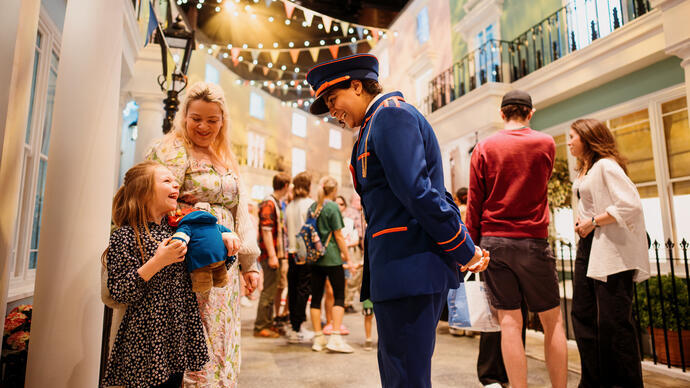 Character actors talking to a young child on the set of a stage.