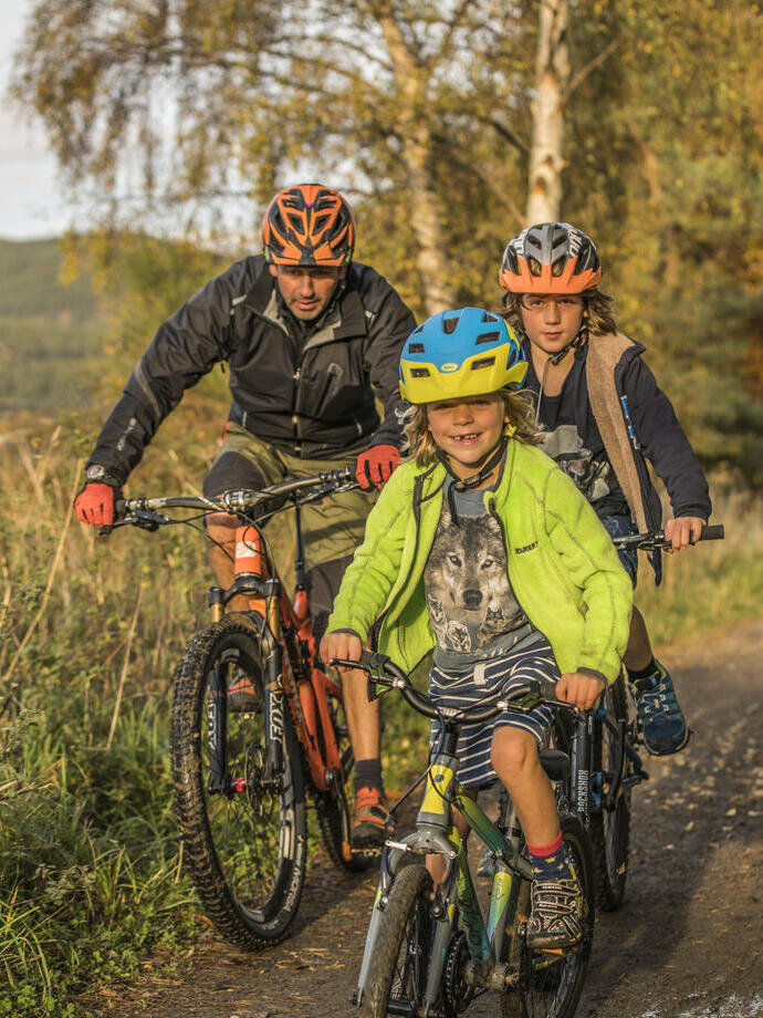 Adult and two children cycling on a path through the countryside