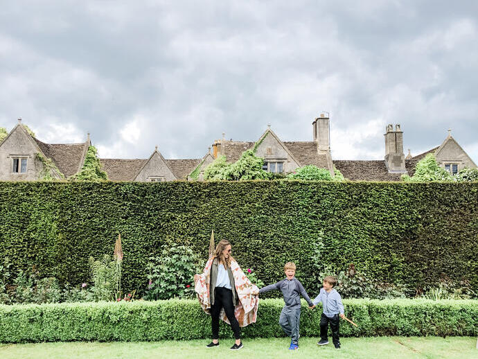 Une mère et ses fils debout dans un jardin devant une haute haie