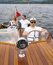 A man and a woman on a boat driven by a skipper on a lake
