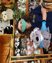 Femme portant un masque facial posant dans un magasin de jouets tout en tenant une peluche