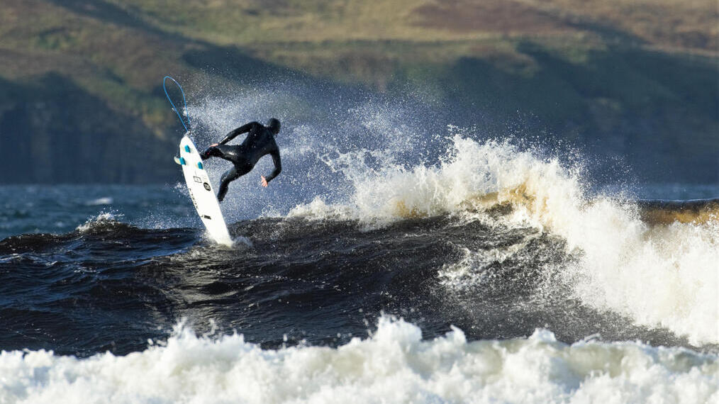 A surfer riding waves off the coast of the UK