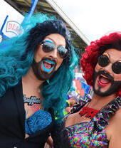 Dos personas con trajes de drag queen sonriendo a la cámara