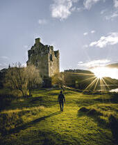 Man walking towards a castle at sunrise