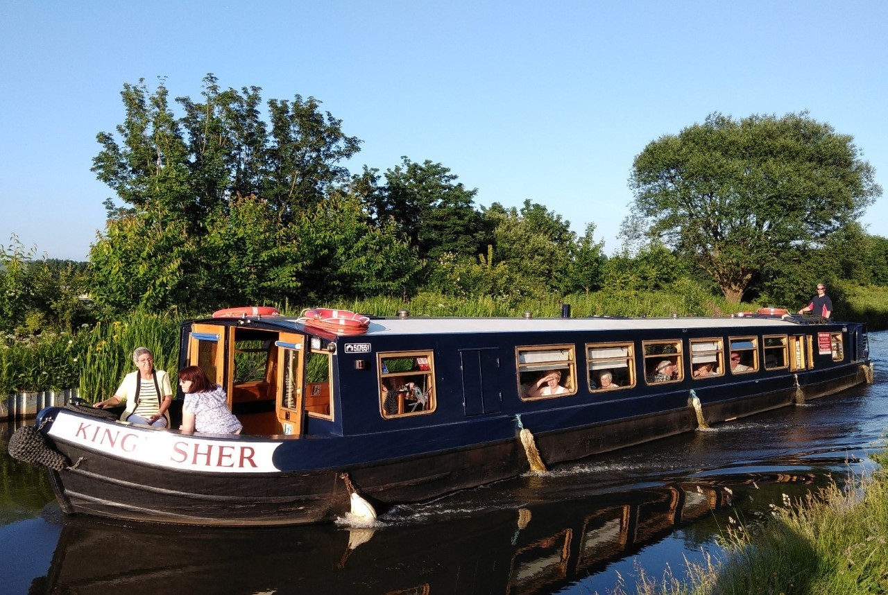 A group of people onboard a barge sailing down a river in Lancashire
