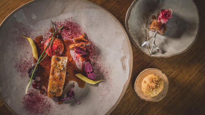 Three different sized plates of colourful food served on rustic grey crockery