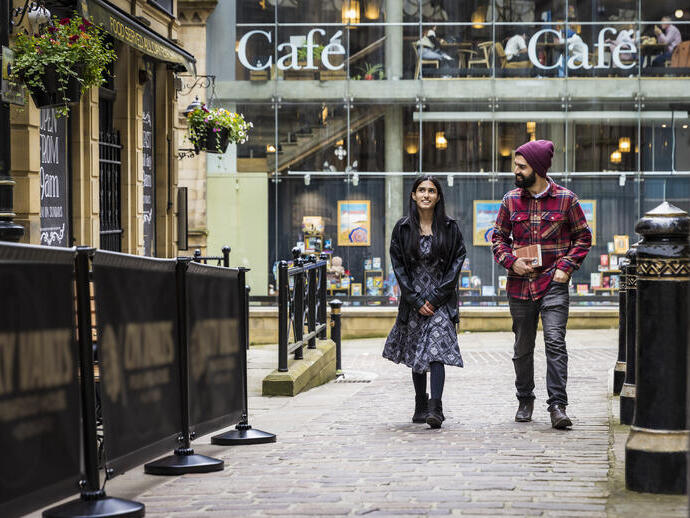 A woman and a man walk through a town centre