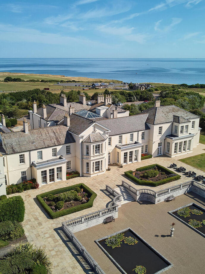 An aerial view of the main hotel building with landscaped garden and ponds at a luxury coastal spa resort