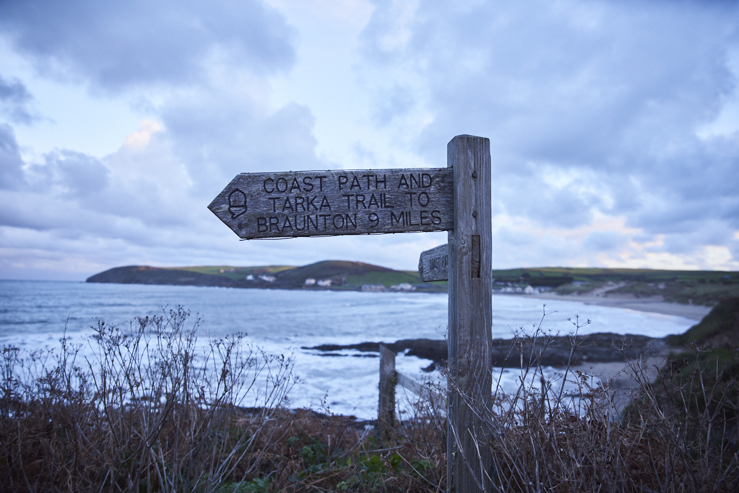 Signpost on the coastal path. Dramatic clouds and seas