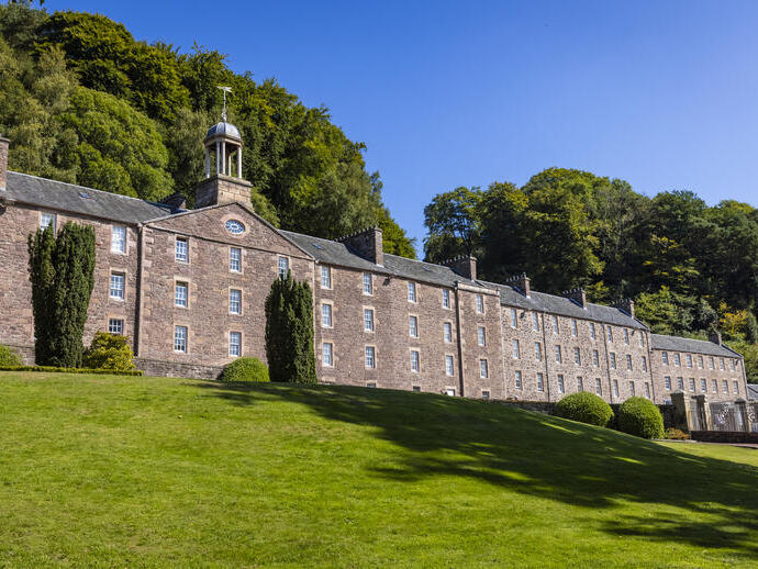 A historic four-storey mill building on a sunny day.