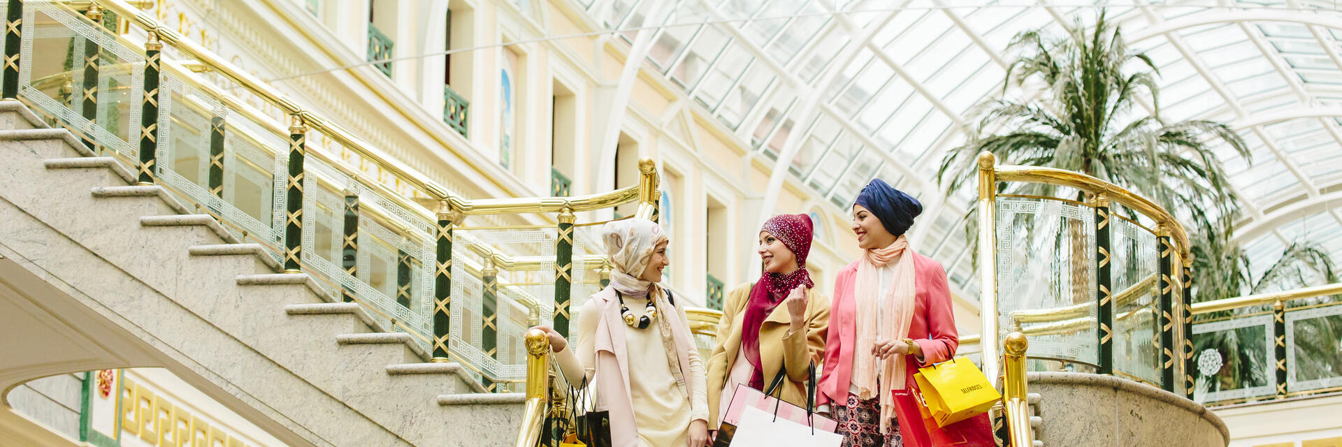 Trois femmes, portant des foulards, marchant avec des sacs de courses