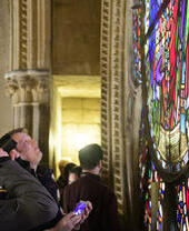 Un grupo de turistas en una visita a la catedral de Lincoln, contemplando una vidriera
