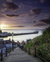 Two people on the steps of a cliff by the sea