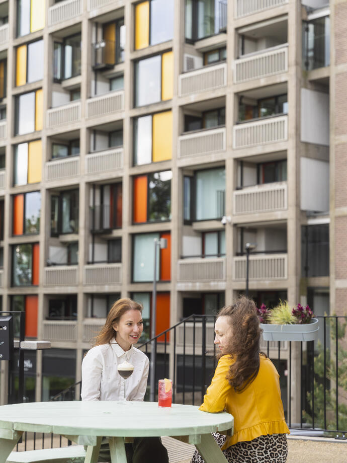 Two women have drinks outside a heritage tower block in a City