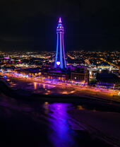 Seaside town at night with tower lit up.