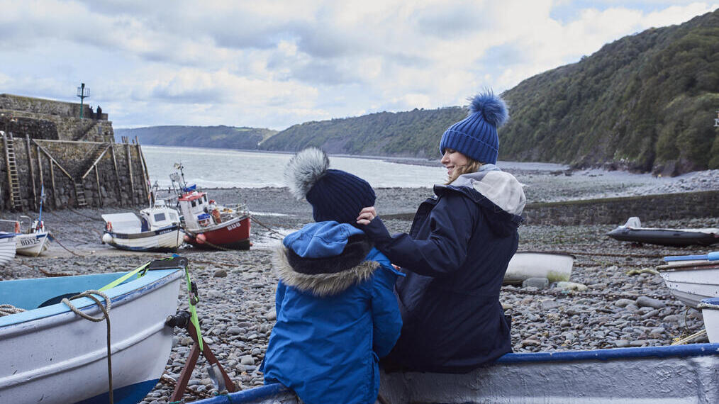 Femme et enfant appuyés sur un petit bateau de pêche dans une crique