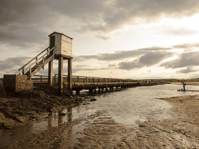 Two people by an elevated causeway at low tide