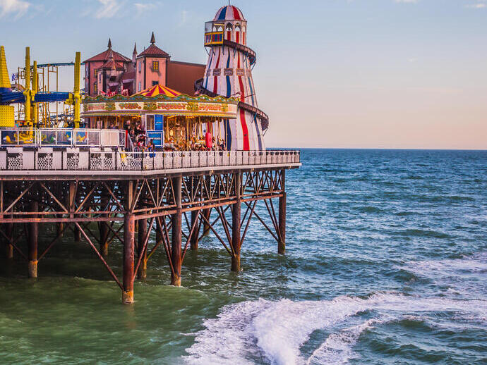 A fun fair on the end of a pier with a jet ski in the sea below