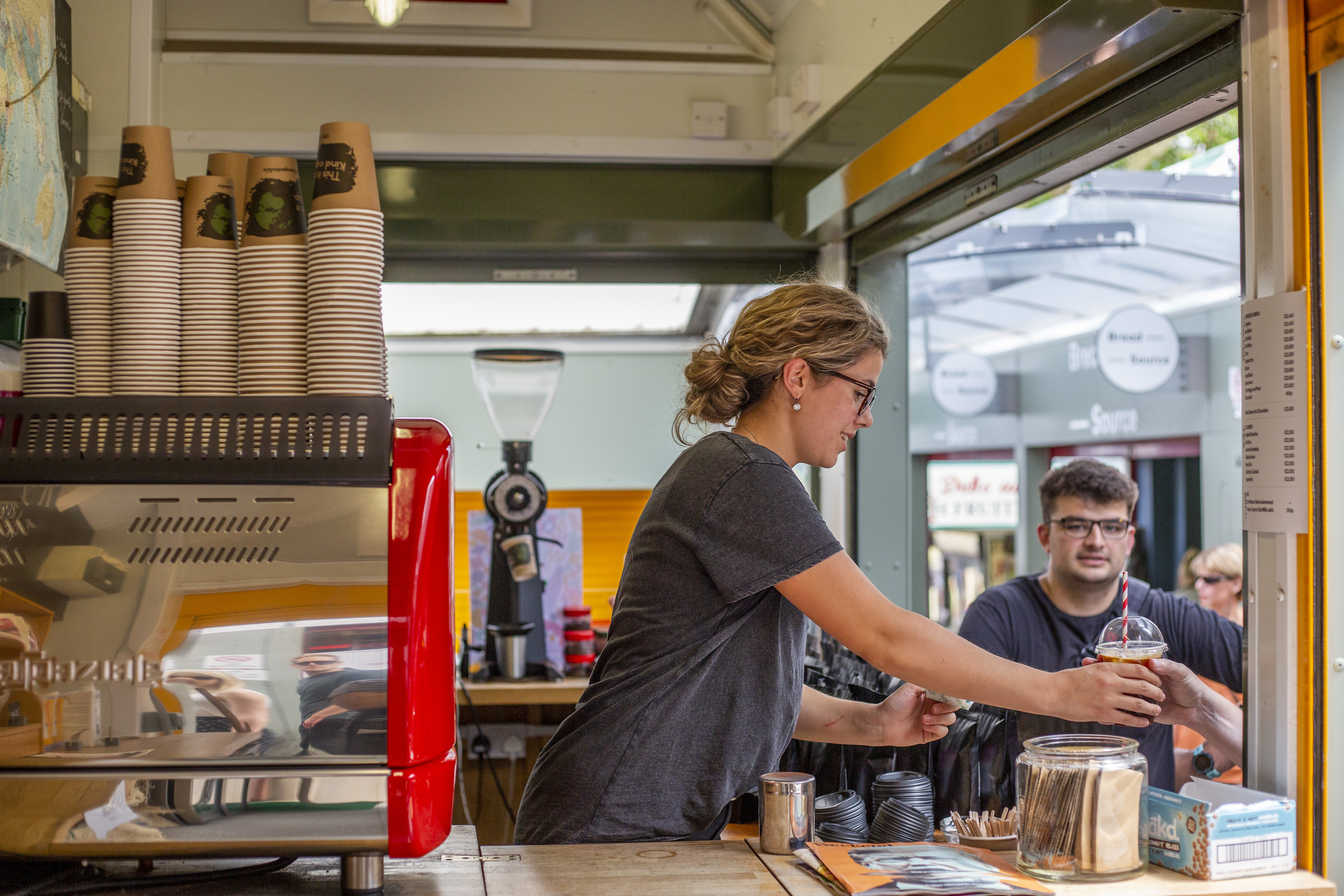 A woman serving drinks at a stall in Norwich Market