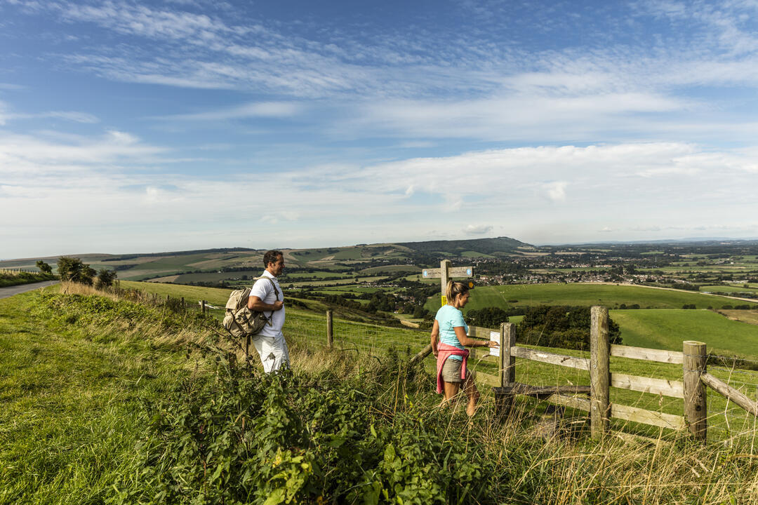 Walkers on path through fields near a direction signpost and a style