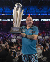 Hombre sosteniendo un trofeo en el Campeonato Mundial de Dardos