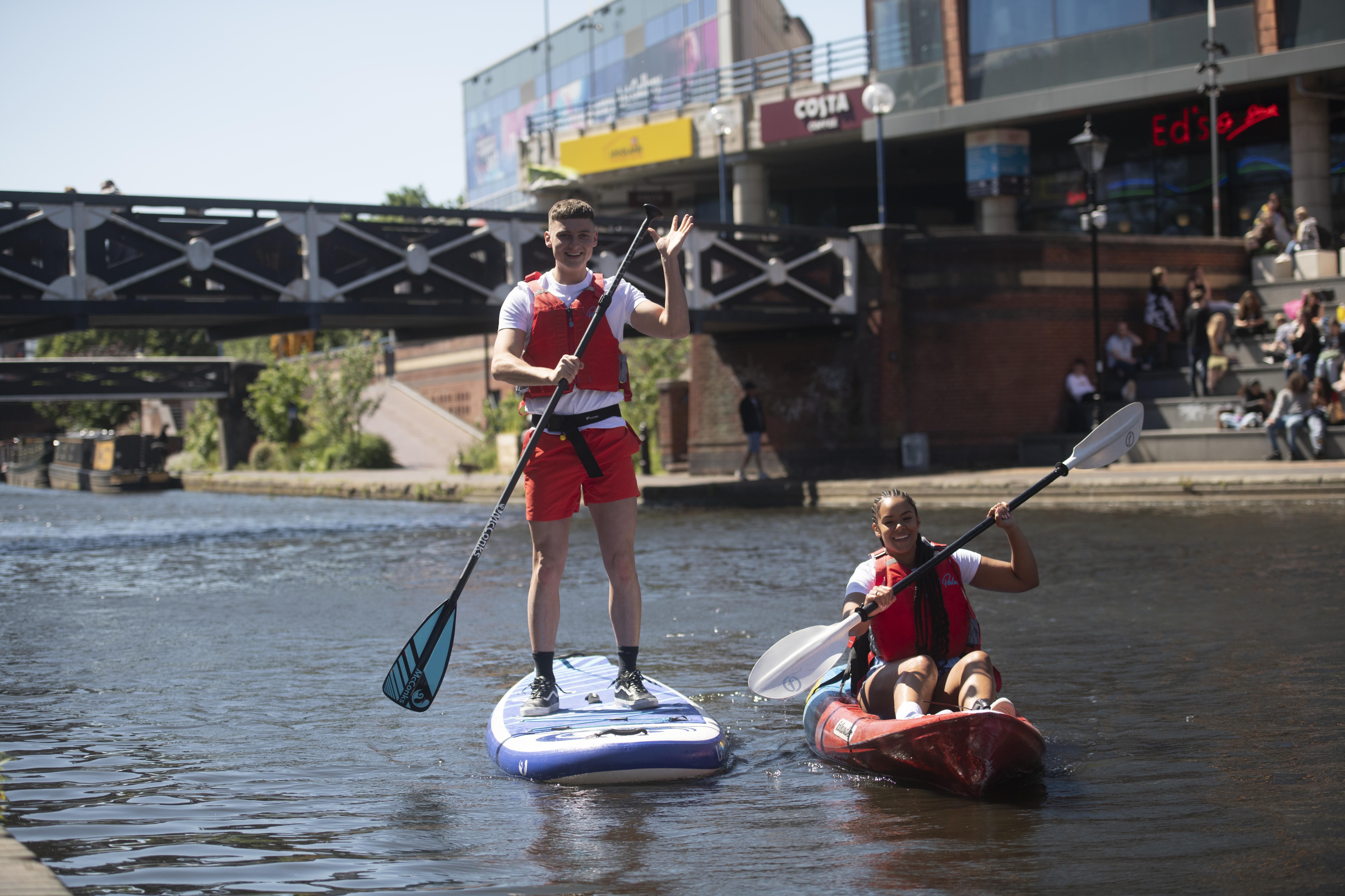 Two men kayaking on canal through central Birmingham