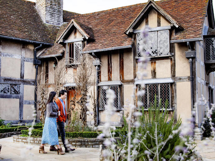 Man and woman walking outside a Tudor house