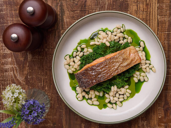 A fish dish at on a kale leaf and beans