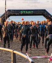Competidores de pie en la línea de salida de una carrera con trajes de neopreno.