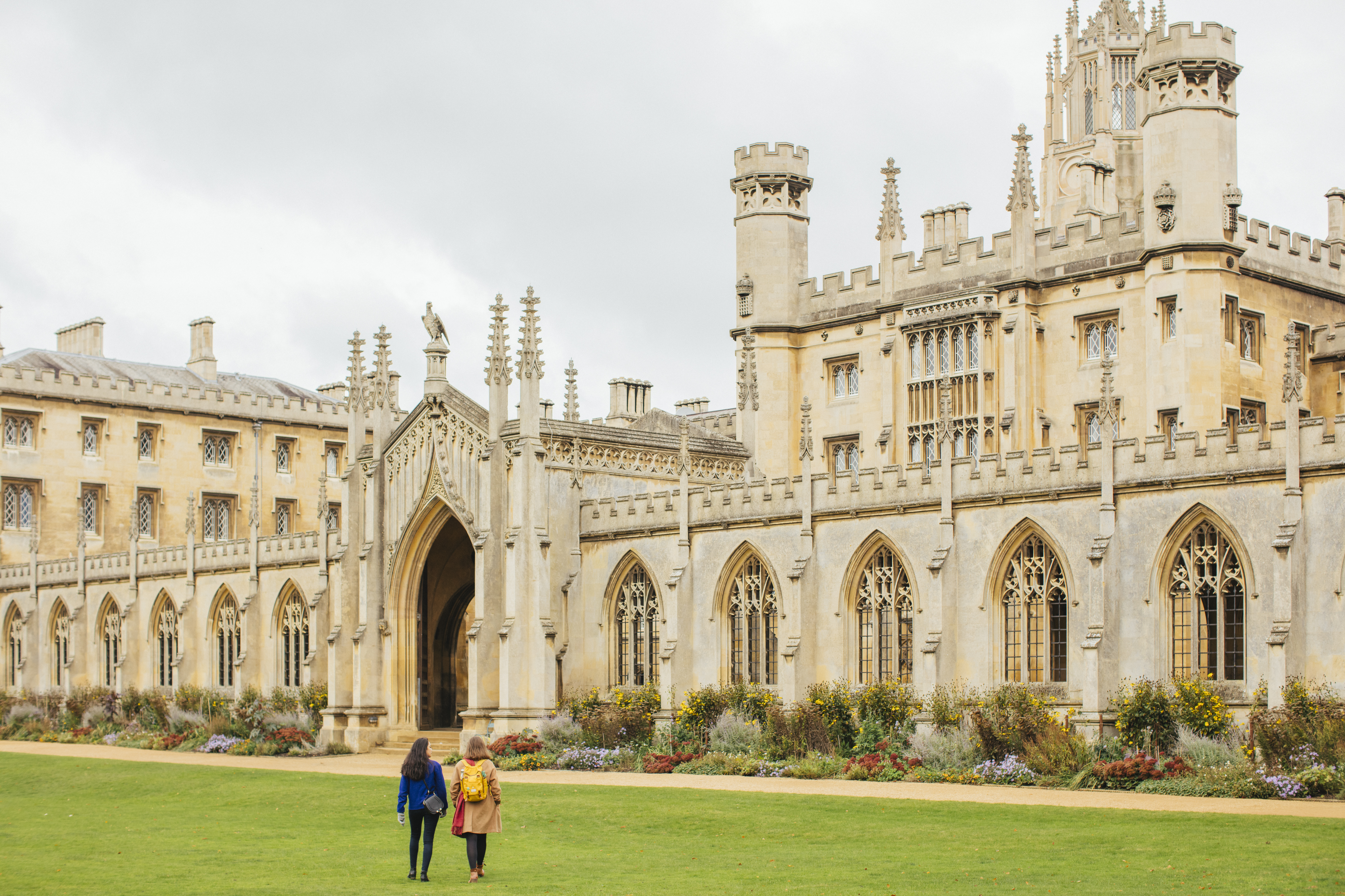 Two women walking across the grass in front of an historic building