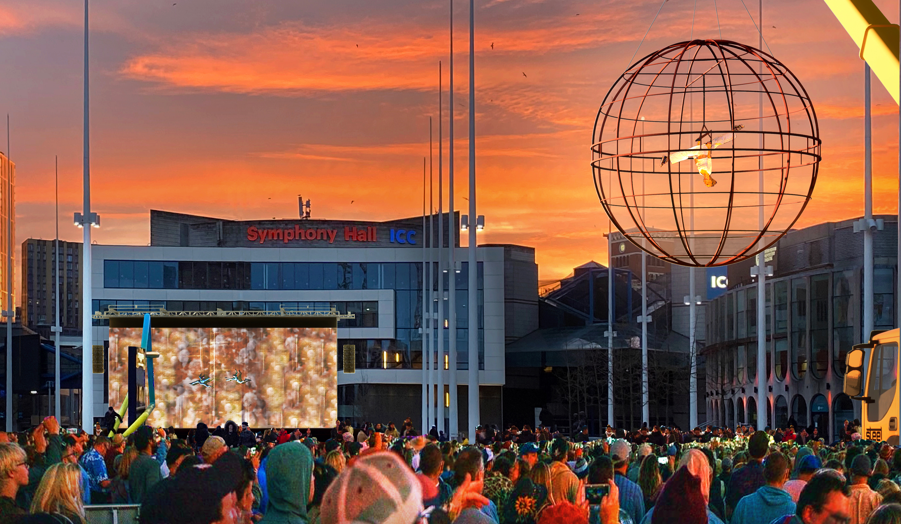 A crowd of people at a festival watching acrobats performing in the air in front of Symphony Hall, Birmingham at sunset