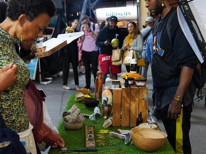 سيدة تنظر إلى عرض كشك في سوق بورتوبيلو النباتي الليلي