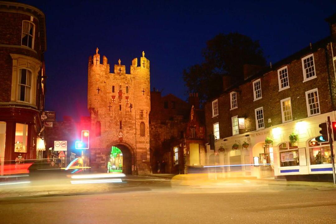 Twilight view of a traffic junction in a city with historic buildings including a tower