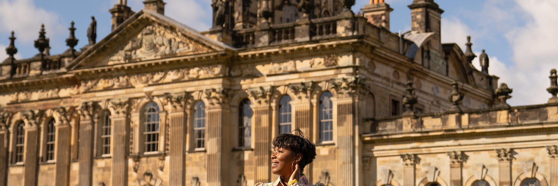 Persona in piedi davanti a un grande edificio storico con cupola dorata in una giornata soleggiata.