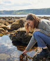 A lady picking seaweed from a rock pool