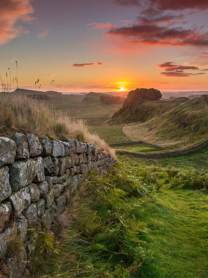 View along long stone wall over the fields at sunset