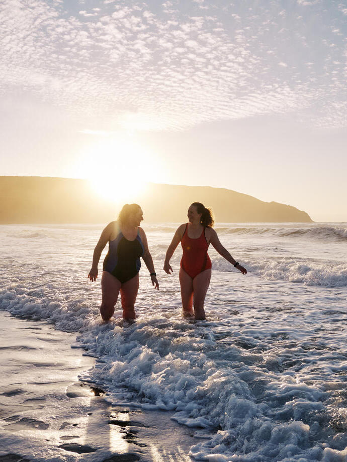 Open water swimmersby the shore at sunset.
