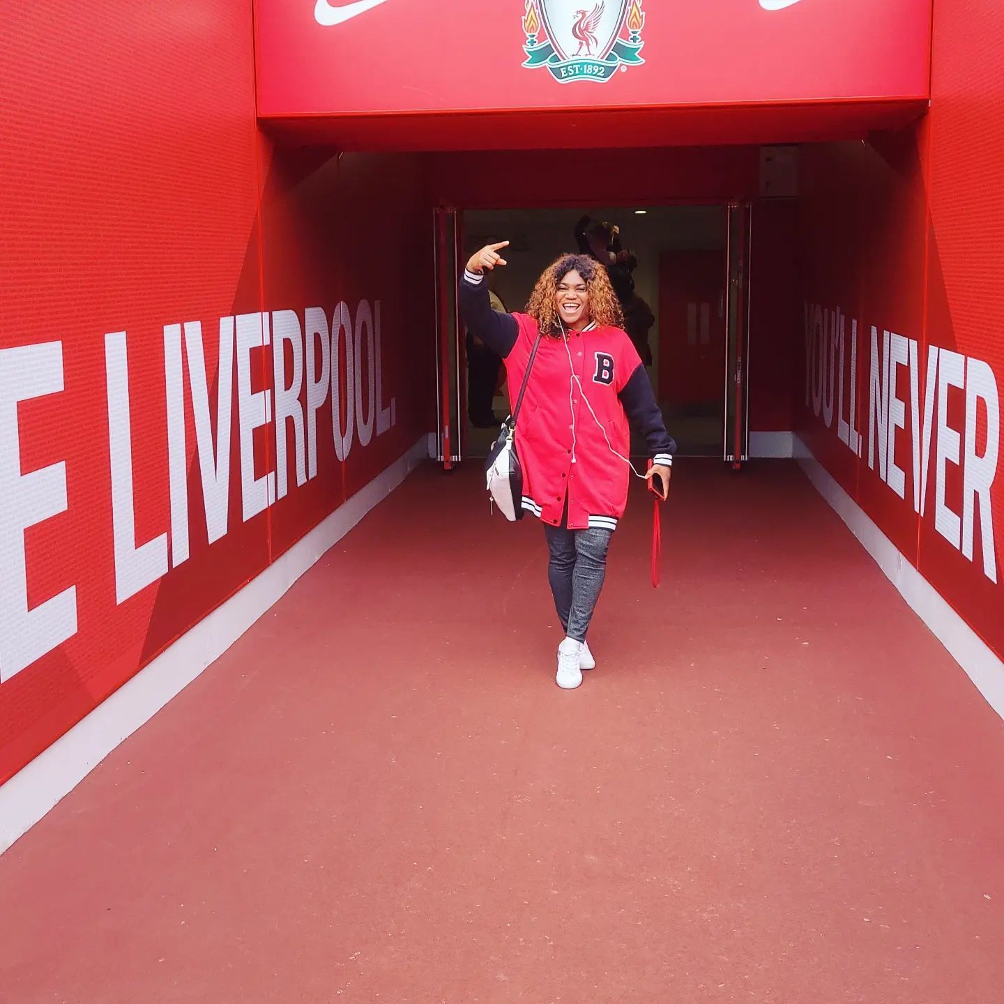 A woman posing while on a stadium tour of Anfield, Liverpool.