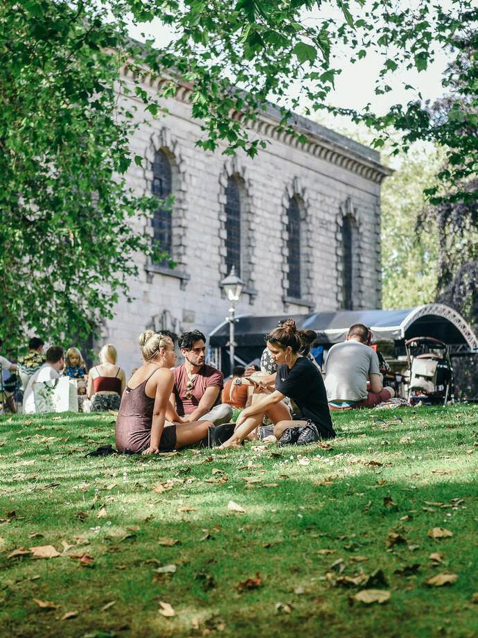 Groups of people sat on a grassy slope in the Jewellery Quarter in Birmingham