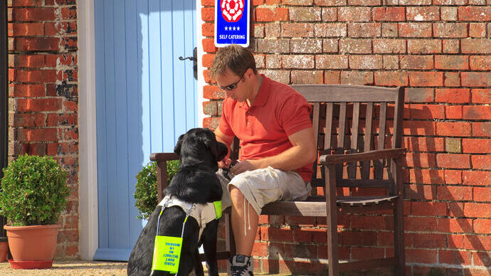 A man sat on a bench with his assistance dog