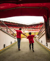 Un hombre y un niño en el túnel del estadio mirando hacia el campo