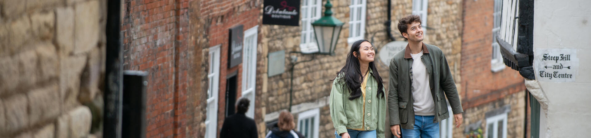 A woman and a man walk up a steep hill in a heritage City