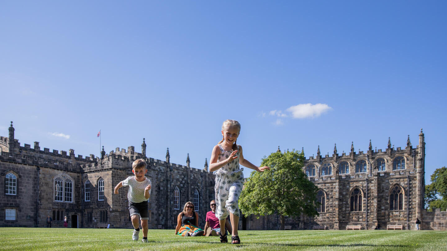 Une famille courant sur la pelouse devant un bâtiment historique à Durham