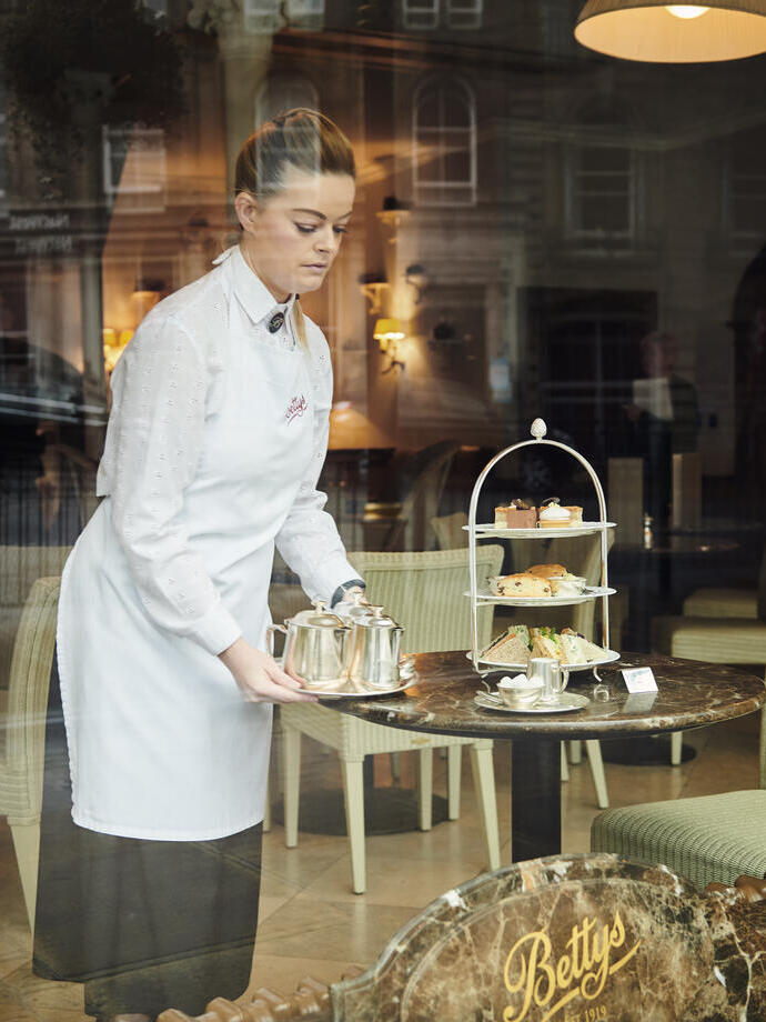 Waitress standing at a table setting up afternoon tea