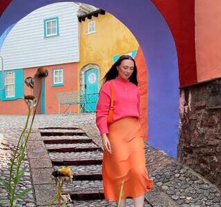 Woman walking on a cobbled street, under a colourful archway
