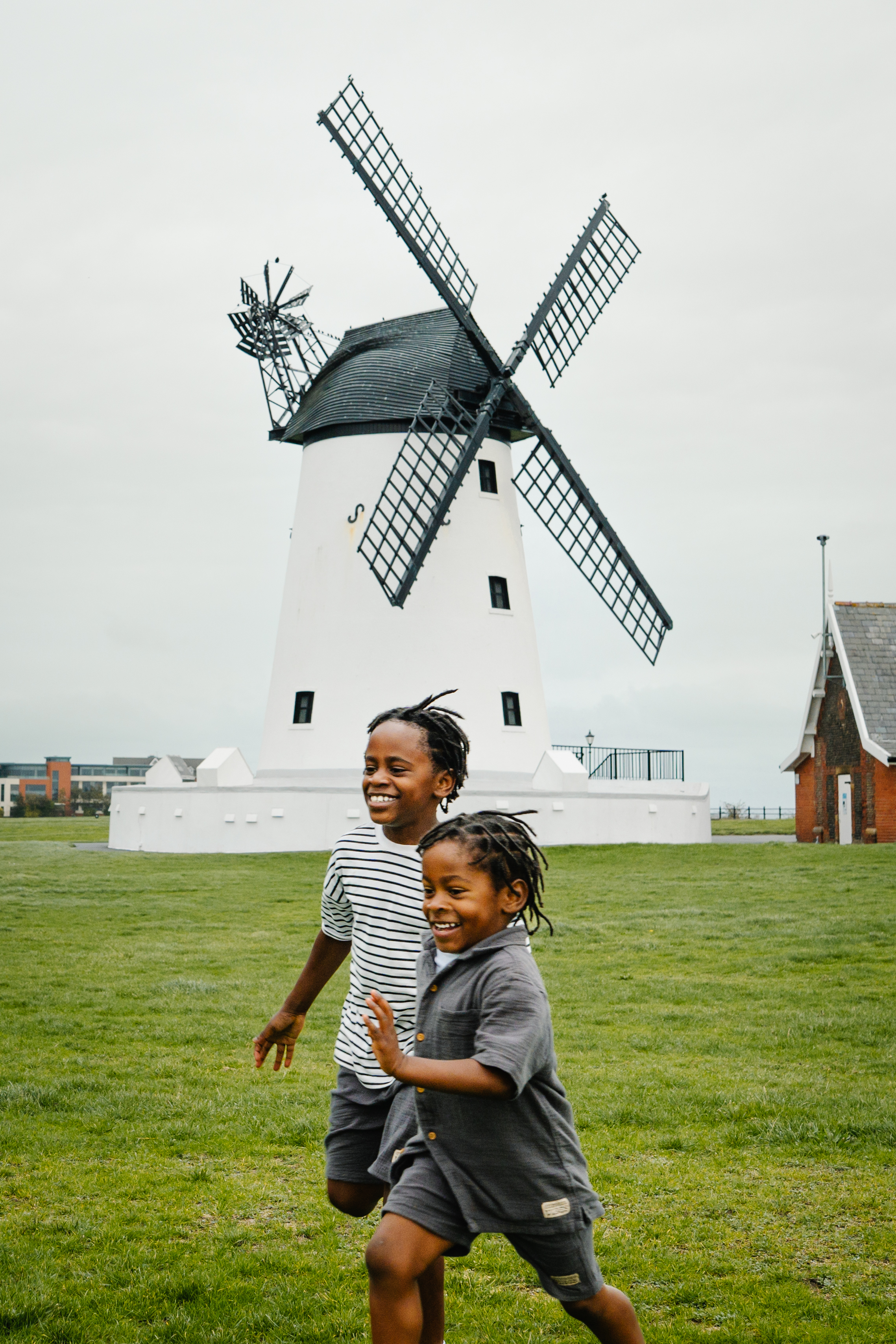 Two young boys having fun on a playing field in front of a windmill