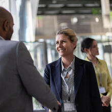 Business professionals interacting and shaking hands in a modern office setting during a networking event.
