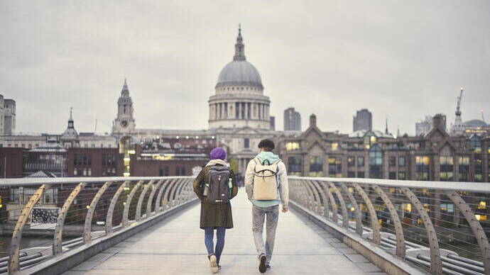 Man and a woman walking on a pedestrian bridge in a city